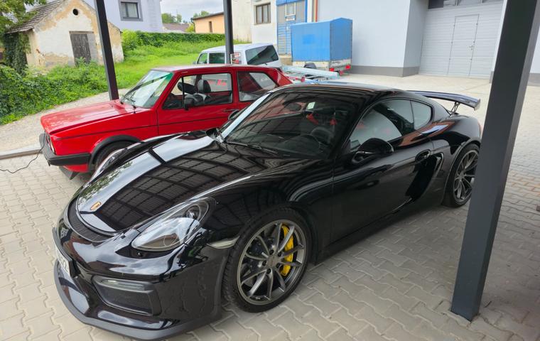 Porsche Cayman a VW Golf pod přístřeškem dílny